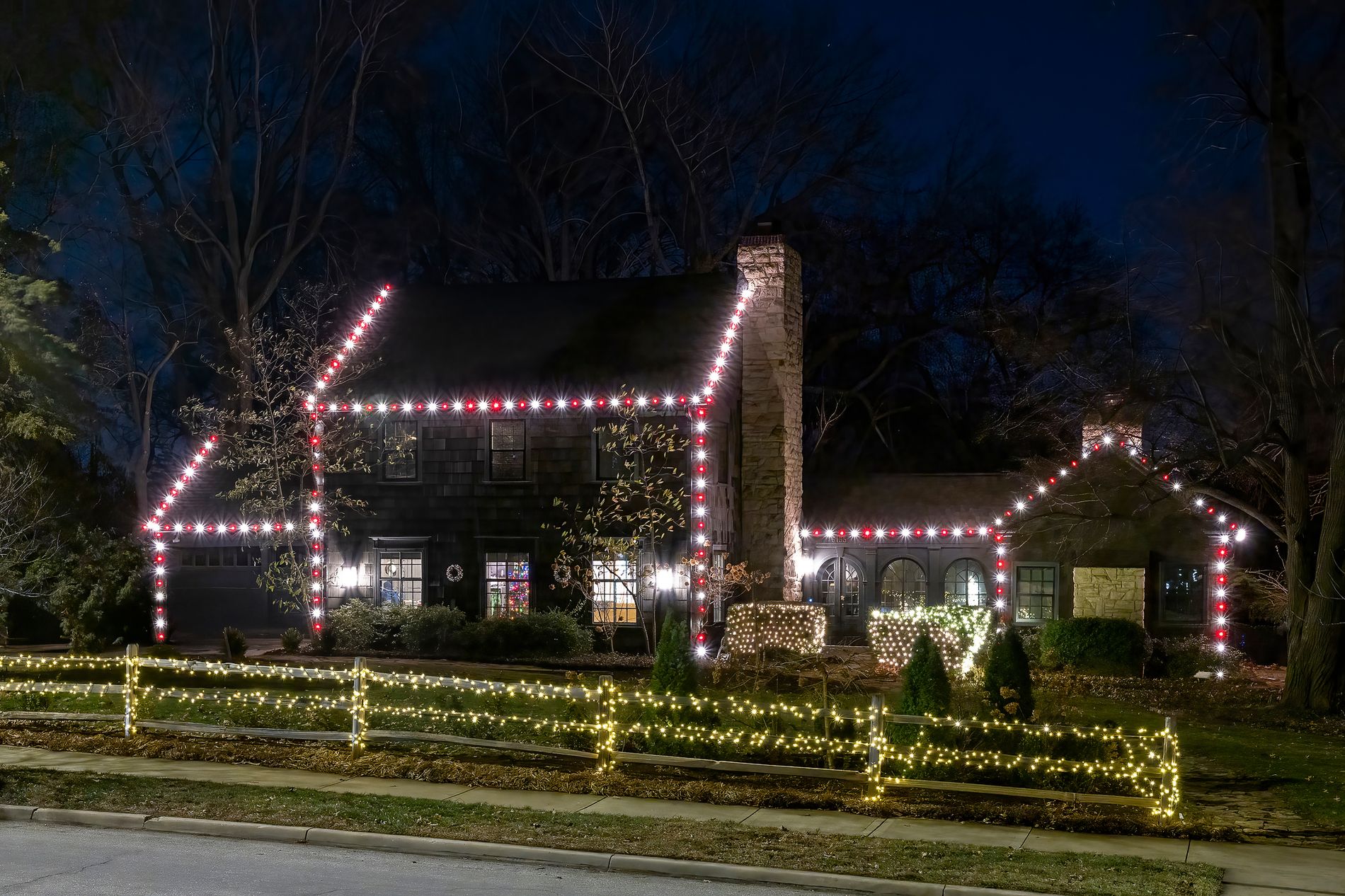 Red and white roofline lighting with a lit fence line