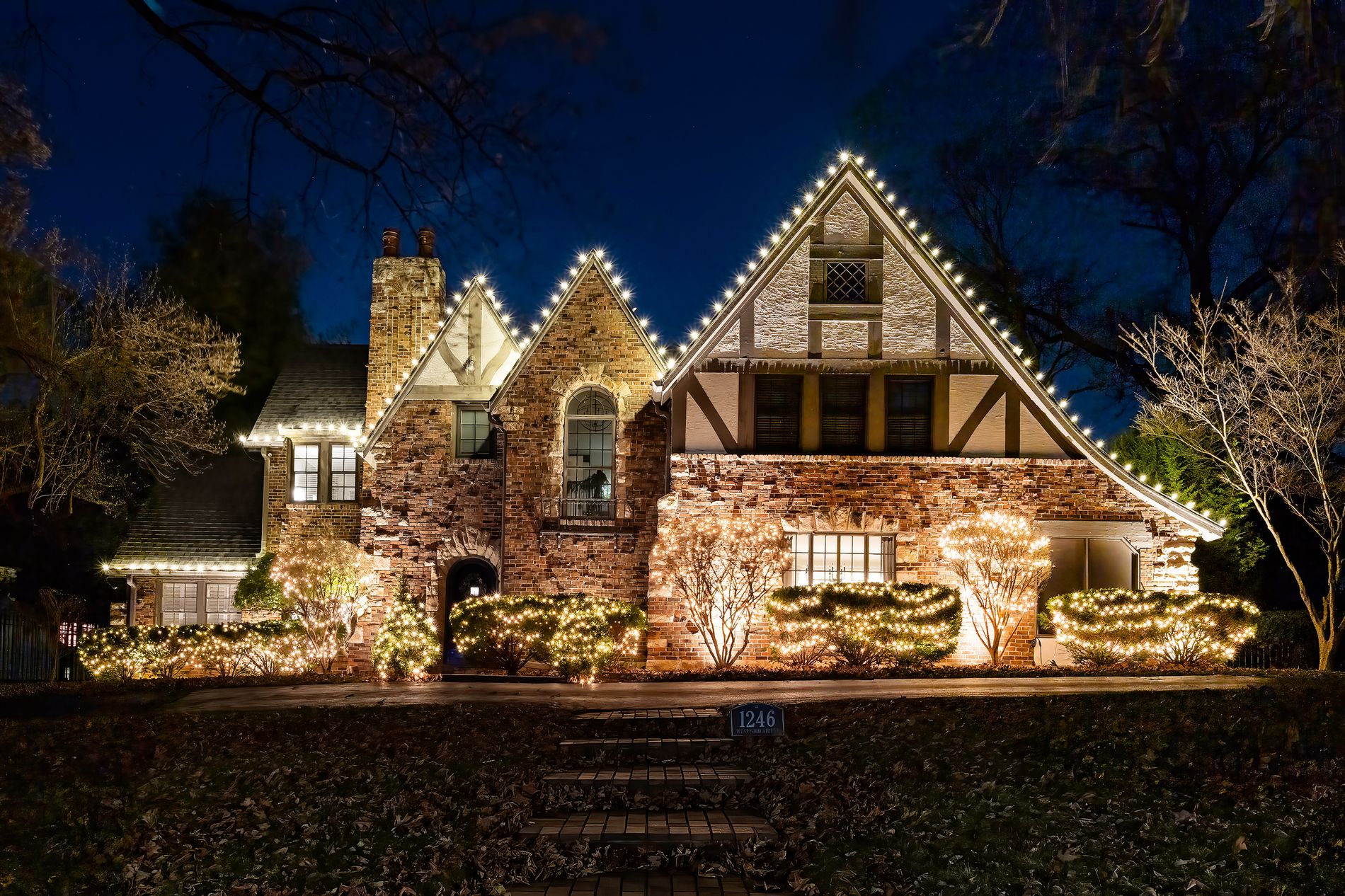 Warm white lighting tracing the gables of a Tudor home